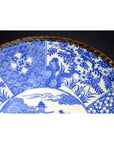 Blue and white porcelain Igezara plate with floral and geometric designs, metal-trimmed edge, close-up view.