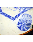 Blue and white porcelain Igezara plate with brown rim, featuring floral and geometric designs, close-up.