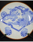Blue and white porcelain Igezara plate with floral design and copper rim, on display stand.