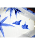 Blue and white porcelain Imari bowl with hand painted birds and bamboo leaves, close-up view.