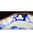 Blue and white porcelain Imari bowl with hand-painted pattern and brown-edged rim, on display.