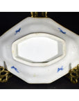Close-up of blue and white porcelain Imari bowl with hand painted designs on decorative brass stand, blue markings visible.