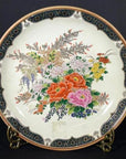 Close-up of an antique Japanese Imari porcelain plate with hand painted floral design and dark blue border on brass stand.