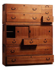 Brown Kiri wood Japanese chest with multiple drawers and sliding doors, some open, antique storage furniture.