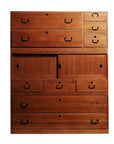 Brown Japanese kiri wood chest with black metal handles and sliding center doors, studio background.