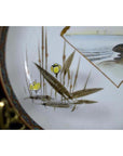 Close-up of an antique Japanese Kutani porcelain plate with hand painted yellow fruit and brown-green leaves by water.