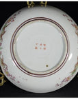 Close-up of the base of an antique Japanese Kutani porcelain plate with floral designs and bold red characters.