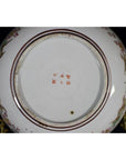 Close-up of the base of an antique Japanese Kutani porcelain plate with red characters and a floral rim border.