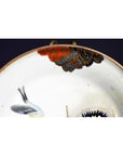 Close-up of antique hand painted Japanese Kutani porcelain plate with bird and floral designs on dark background.