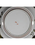 White porcelain plate underside with red circular lines and a small central red maker’s mark, close-up view.
