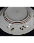 White porcelain plate with red lines and small colored floral motifs on base, antique style.