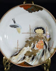 Close-up of a multicolor hand painted Japanese Kutani porcelain plate with birds, gold leaves, and floral design on stand.