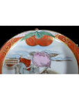Close-up of antique Japanese Satsuma ceramic plate with red and gold border, hand painted fruit and leaf design.