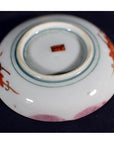 Close-up of a red floral hand painted Japanese Satsuma porcelain plate with brown label on base.