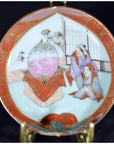 Close-up of antique Japanese Satsuma porcelain plate with hand painted figures in traditional dress and large indoor vase.
