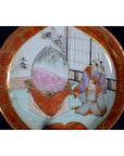 White ceramic Satsuma plate with two figures and a child beside a giant peach in a traditional Japanese scene.