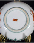 Close-up of the underside of an antique Japanese Satsuma porcelain plate with red-green designs and red rectangular mark.