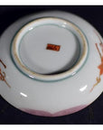 Red ceramic plate with hand painted floral designs and red base mark, displayed on a dark background.