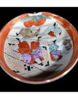 Close-up of colorful hand-painted figures and patterns on a black porcelain antique Japanese Satsuma plate.