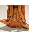 Close-up of orange and gold ornate robe on antique Japanese Taisho samurai doll lower body, fabric detail visible.