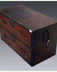 Brown wood Japanese Tansu chest with metal handles, side lock, and two large drawers against gray background.