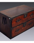 Brown wooden Japanese Tansu with two large drawers, metal handles, and corner reinforcements on gray background.
