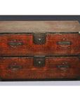 Dark wood Japanese Tansu with two large drawers, metal handles and corner brackets, shown on a gray background.