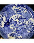 White porcelain Japanese transferware plate with blue floral and landscape patterns, antique style, close-up.