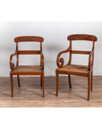 Brown wooden and rattan Javanese armchairs with carved backs, side by side on a wooden floor indoors.