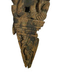 Brown wood temple carving, mirrored Burmese guardian relief with stylized headgear, floral and geometric motifs.
