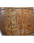 Close-up of brown ceramic jar with embossed floral and pillar patterns in geometric shapes.