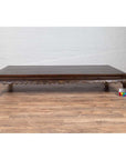 Dark wood Ming Dynasty style Kang opium bed with hand-carved legs on a wood floor next to a color calibration card.