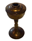 Brass oil lamp with round body, slender stem, and flared base on white background.