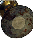 Close-up of brass antique oil lamp base with visible rust and tarnish on the underside.