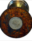 Close-up of rusted brass base of antique oil lamp with circular gray patch in center.