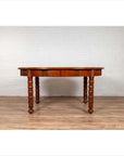 Brown wood oval dining table with spindle legs and warm patina on wooden floor, Indonesian antique style.