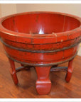 Close-up of an antique red lacquer wash basin with a round shape, legs, and worn paint for a rustic 19th-century look.