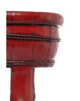 Close-up of antique red wooden basin with carved textured details, set against a plain white background.