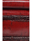 Close-up of antique red wooden basin with weathered finish, visible seams, and surface scratches.
