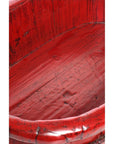 Close-up of distressed red lacquered wooden basin showing textured scratches and rounded edge.