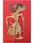 Red background, leather antique shadow puppet with intricate Indonesian patterns, close-up view.