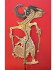 Red background, leather antique shadow puppet with intricate Indonesian patterns, close-up view.