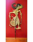 Gold and red leather Indonesian shadow puppet, close-up, displayed against a vibrant red background.