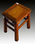 Close-up of a small, square rustic Chinese elm stool with thick legs on a gradient background.