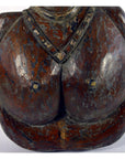Brown wooden Sumatra fertility mask bust with necklace, prominent breasts, and worn paint, close-up view.