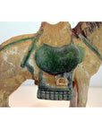 Glazed terracotta horse with green saddle, side view, Ming Dynasty style against plain background.