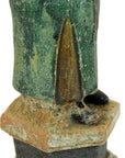 Close-up of brown terracotta court figure statue feet and lower robe on weathered square pedestal.