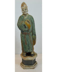 Green terracotta court figure statue with hat on hexagonal base, close-up view.