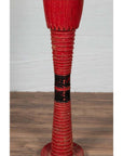 Red ribbed ceramic vase with round base, tall design, inspired by Antique Thai ceremonial drums, on plain background.