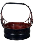 Close-up of a black and red antique Thai basket with large handle and bold circular cutouts on the sides.